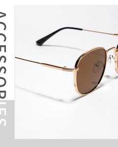 Detail view of gold metal sunglasses frame with vintage tea-colored lenses and black tips