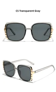 Detail view of transparent grey square sunglasses with golden temple accents and grey lenses