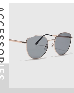 Close-up of rose gold metal cat-eye sunglasses with grey lenses and black earpieces
