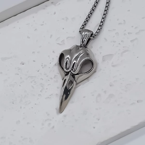 Collana con ciondolo a teschio di uccello argentato e catena a scatola su fondo bianco