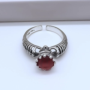 Macro detail of gothic S925 silver ring featuring red gemstone and carved rib cage pattern