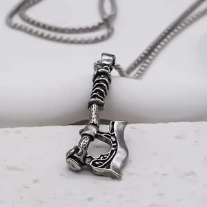 Detailed macro view of vintage silver axe pendant with Nordic engravings on box chain