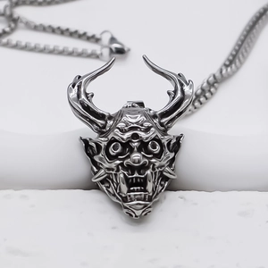 Nahaufnahme eines silbernen Dämonen-Maskenanhängers mit gotischen Texturen und Metallfinish