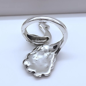 Macro detail of silver peacock ring showing irregular hammered texture and feather design