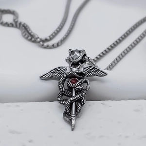 Macro shot of vintage Caduceus serpent pendant with a ruby red center stone and wings