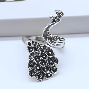 Macro detail of silver peacock ring showing intricate antique-style engraved feathers