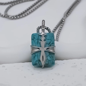 Detail of square turquoise pendant with silver cross inlay on polished foxtail chain