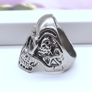 Macro detail of silver skull ring showing intricate side engravings and punk metal finish