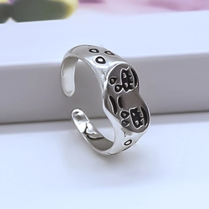 Detailed view of silver punk ring featuring a black enamel crying face cartoon design