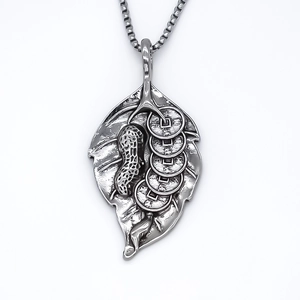 Vintage silver leaf pendant necklace with peanut and ancient coin charms on white background