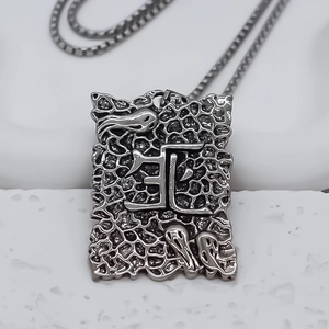Detail of square ghost pendant with dark silver texture and Chinese character carving