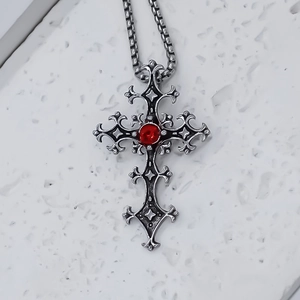 Detail of gothic stainless steel cross pendant with red gemstone and box chain link