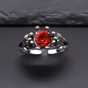 Vintage silver crown ring with a central red gemstone on a dark textured rock background