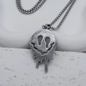 Close-up of punk style melting face pendant with retro silver box chain on stone decor