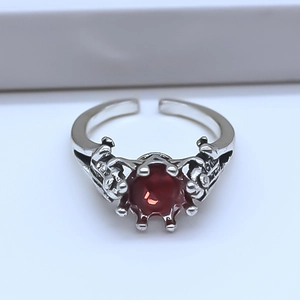 Macro shot of gothic alloy crown ring featuring a large red ruby and skull claw design
