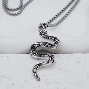 Macro shot of silver snake pendant with scale texture and vintage finish on long chain