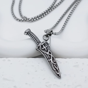 Detail shot of vintage silver embossed dagger pendant with textured gothic engravings
