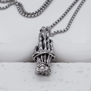 Close-up of retro silver skull hands prayer pendant with a classic box chain necklace