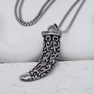 Detailed view of punk-style horn pendant with flame carvings on round box chain