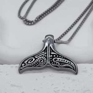 Détail macro du pendentif queue de poisson en argent vintage avec reliefs tribaux