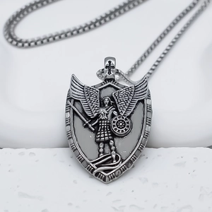 Macro detail of vintage silver shield pendant with archangel relief on curb chain