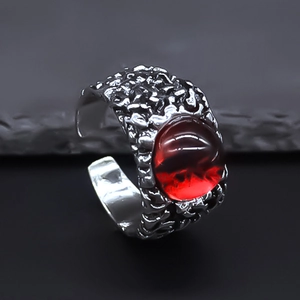 Macro view of gothic red evil eye ring featuring raw molten metal texture and red stone