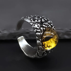 Macro detail of silver metal ring with lava texture and a translucent yellow evil eye