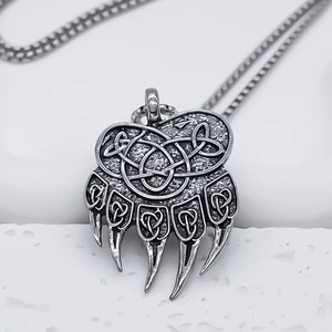 Macro shot of Viking Celtic knot bear paw pendant with vintage silver finish on white stone
