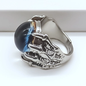 Macro shot of a gothic silver skeleton claw ring holding a deep blue gemstone sphere