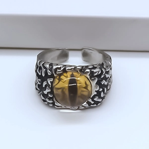 Macro detail of gothic evil eye ring featuring amber eyeball and aged metal texture