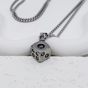 Macro detail of silver dice pendant with skull dots on punk style box chain necklace