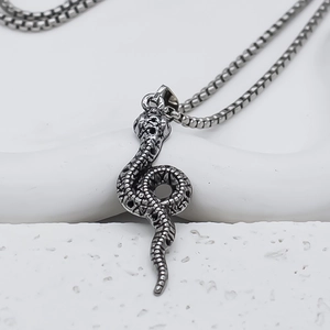 Macro shot of a vintage silver snake pendant with detailed scales on a box chain link