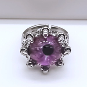 Gros plan d'une bague gothique avec œil de démon violet et griffes de monstre en alliage argent