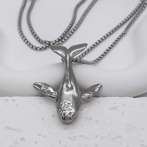 Macro detail of silver whale pendant with textured head and smooth polished finish