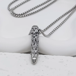 Detail of a punk skull bullet pendant with vintage engraving and silver box chain