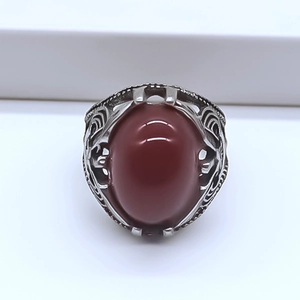 Close-up of vintage silver ring featuring a large oval red stone with hollow patterns