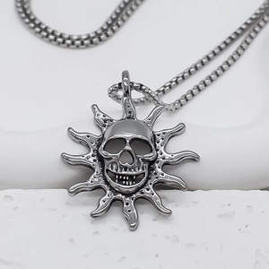 Macro view of dark gray punk skull pendant with sunburst texture and box chain