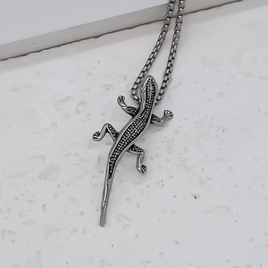 Close-up of silver lizard pendant with scale texture on a classic box chain necklace