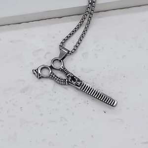 Detailed macro of vintage stainless steel scissors and comb pendant with floral engraving