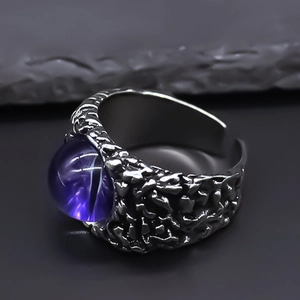 Close-up of gothic dark ring with purple eagle eye stone and textured metal band