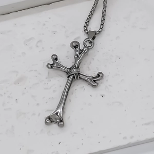 Macro shot of silver stainless steel box chain with a gothic cross bone pendant
