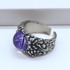 Detail of vintage punk open ring with purple eagle eye stone and distressed metal finish