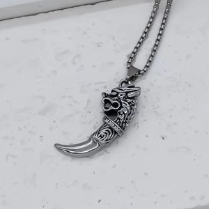 Detail of vintage silver dragon head pendant with claw design and engraved scales