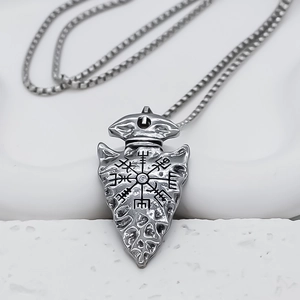 Macro detail of silver triangular arrow pendant with Nordic Vegvisir compass engraving