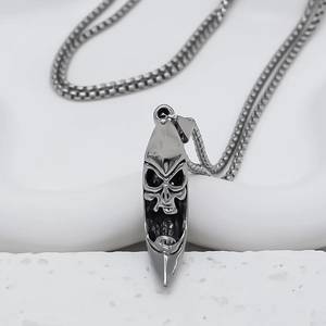 Macro shot of silver crescent moon necklace with embossed skull and square pearl chain