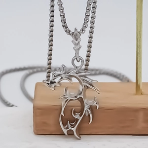 Silver dragon pendant necklace with box chain displayed on a minimalist wooden stand