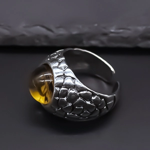 Close-up of punk style silver alloy ring with dragon scale texture and amber resin stone