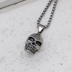 Collier avec pendentif tête de mort argenté vieilli sur chaîne box et fond marbre