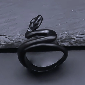 Detailed macro view of a matte black coiled snake ring on a textured stone surface
