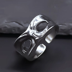 Close-up of vintage silver mask-style open ring on textured grey stone surface